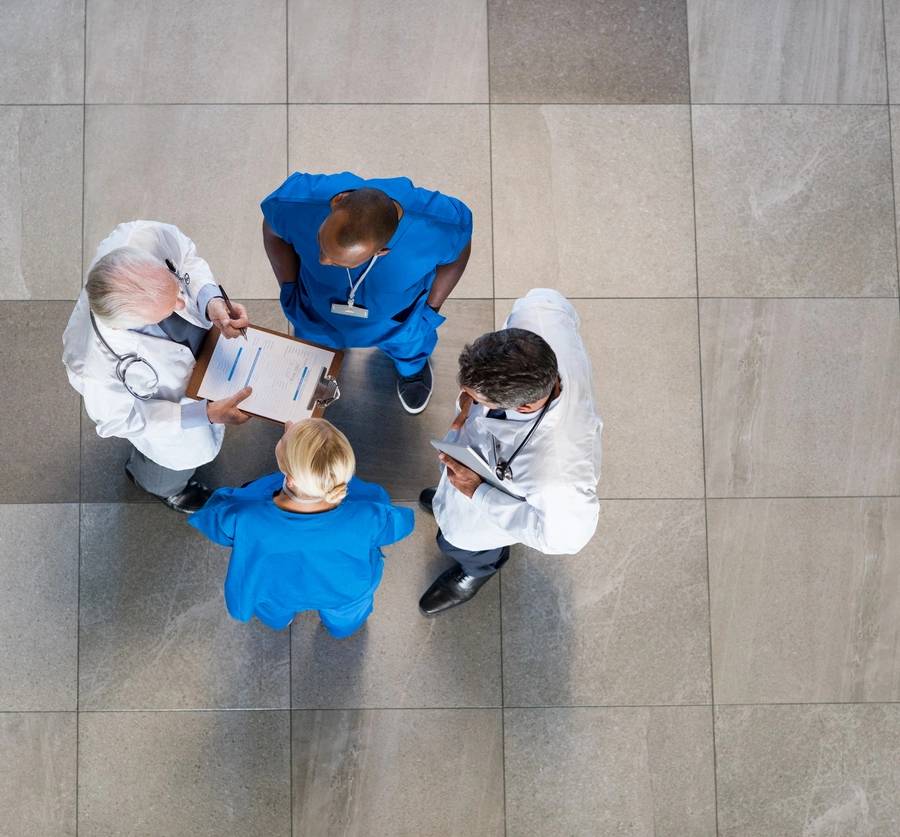 High angle view of senior doctors and young surgeons discussing over patient case. Top view of group of doctor in a conversation with copyspace. Doctors and nurses talking to each other about medical results. (High angle view of senior doctors and you